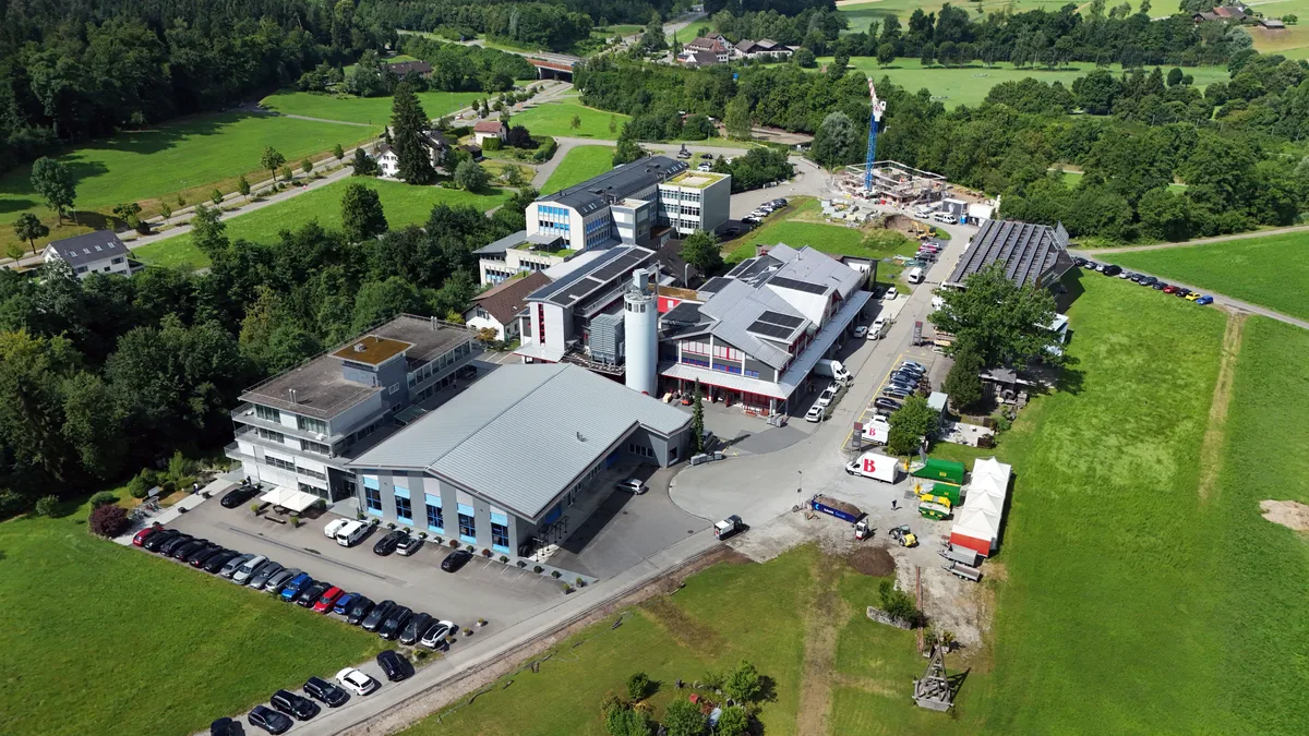 Luftaufnahme der Bertschinger Innenausbau AG in Bubikon. Man sieht einen Gebäudekomplex auf der grünen Wiese.